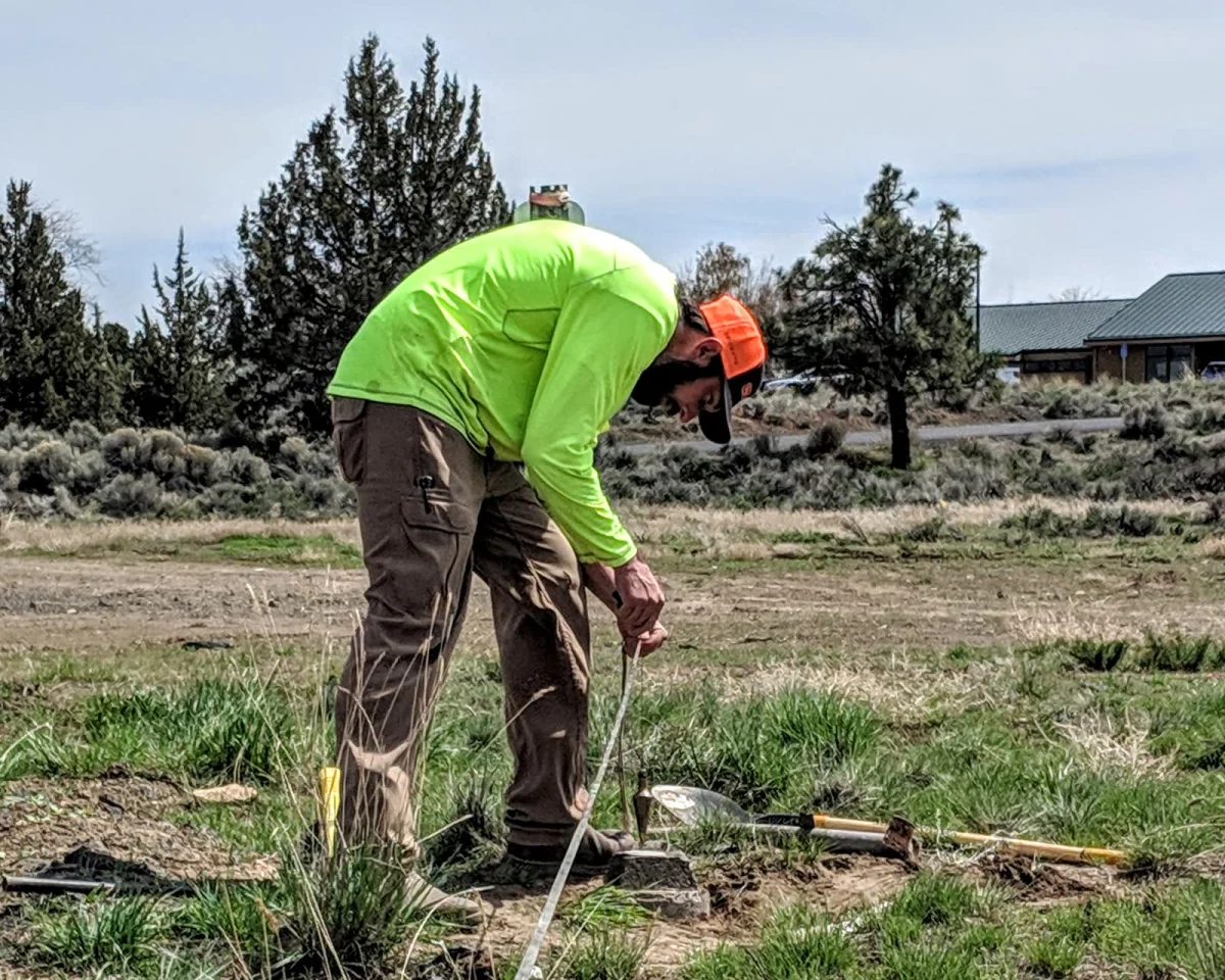 Surveyor using a tape measure while setting a property monument